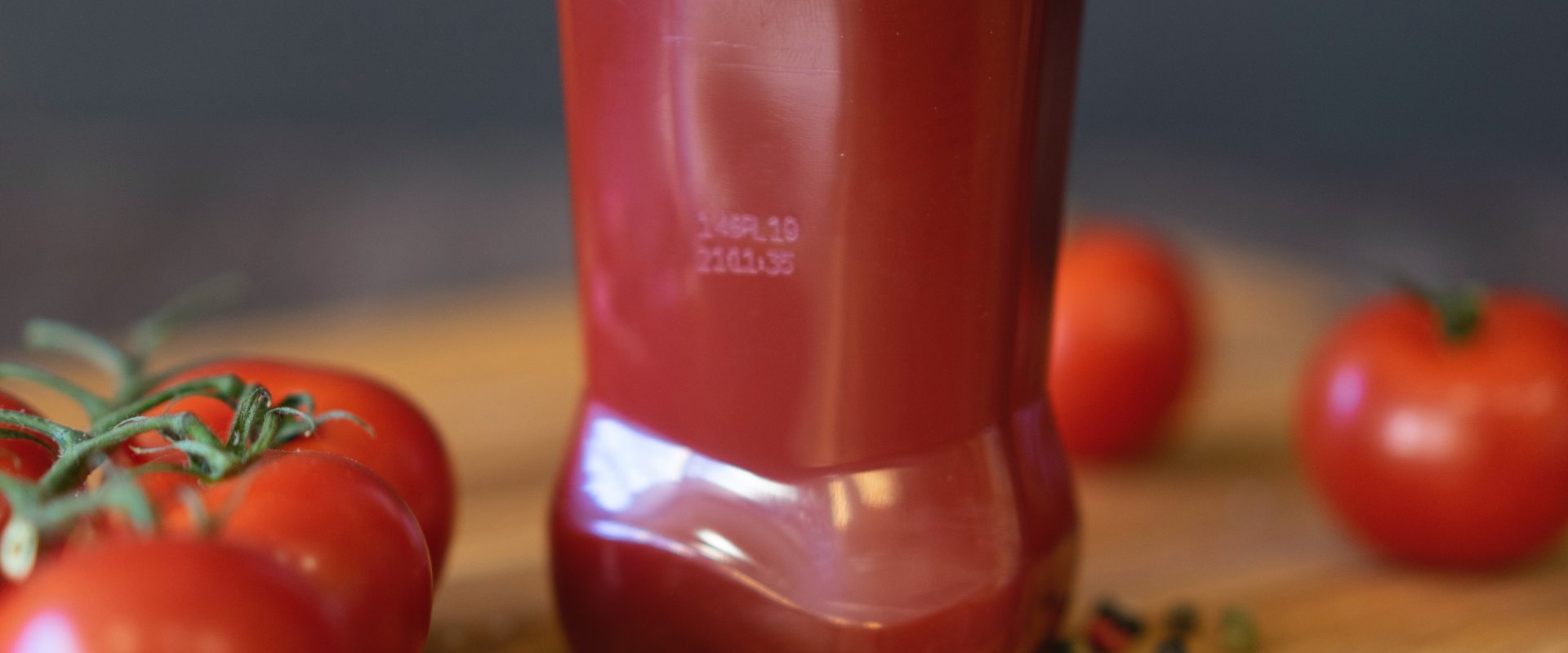 Ketchup bottle with tomatoes on table