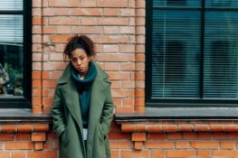 Sad woman leaning on a brick wall.