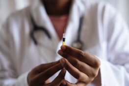 A medical personnel holding an injection, about to administer a vaccine - getting Vaccinated