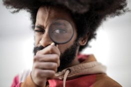 person-in-red-and-brown-jacket-holding-magnifying-glass-
